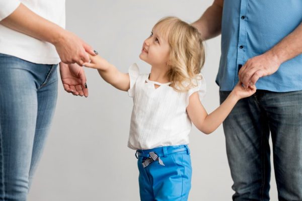 Niña con sus dos progenitores durante un proceso de custodia de hijos